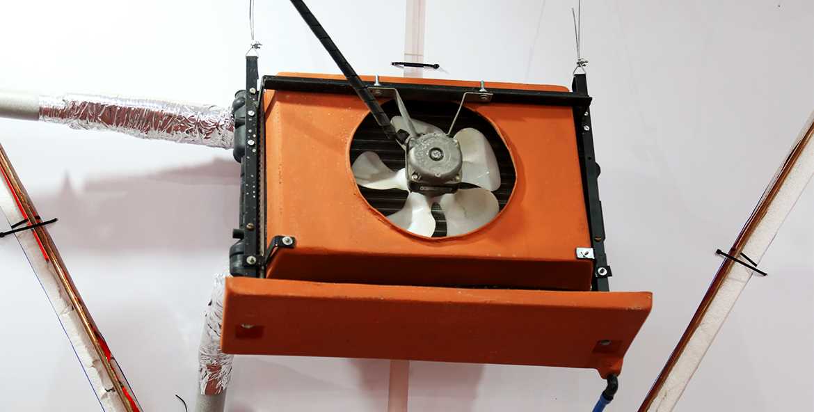 Fan coil caseiro de cor laranja feito com radiador automotivo com uma ventoinha pra fora montado na parede